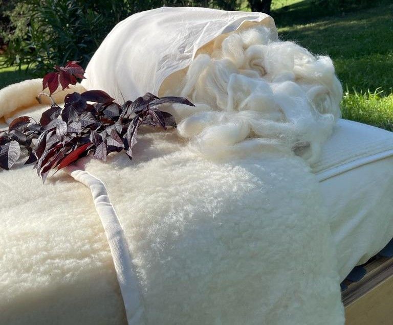 Almohada y manta de lana merina ecológica de La Cama Azul sobre ropa de cama de algodón orgánico